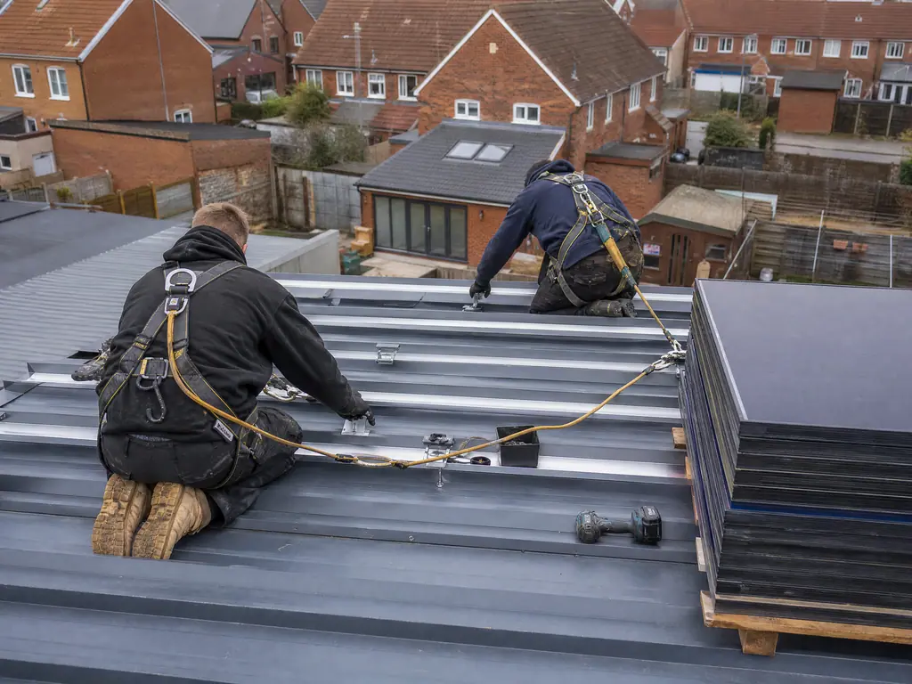 Installers fixing mounting rails to a metal commercial roof, Birmingham
