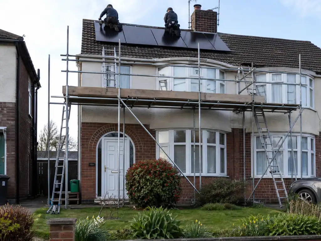 Installers on a scaffold fitting solar panels to a semi-detached house in Solihull