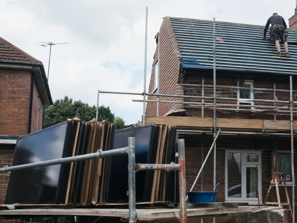 Solar panels removed and stacked on a scaffold while a Birmingham roof is replaced